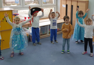 Dzieci tańczą przy piosence trzymając ręce uniesione w górze.