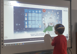 Chłopiec segreguje bałwanki według rozmiaru na tablicy interaktywenj.