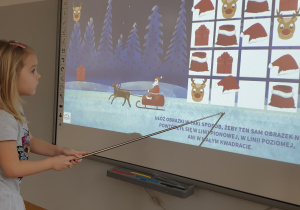 Dziewczynka rozwiązuje świąteczne sudoku na tablicy interaktywej.