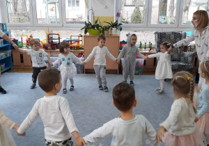 Dzieci tańczą w kole trzymając się za ręce.