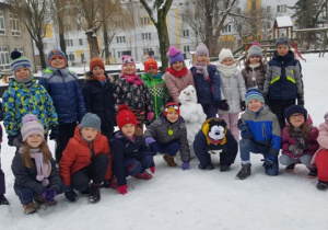 Zdjęcie z bałwanem. Wszystkie dzieci skupiły się wokół śnieżnego przyjaciela.
