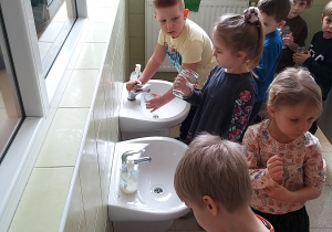 Dzieci nalewają w łazience wody do słoików.