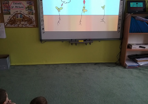 Dzieci oglądają na tablicy interaktywnej film edukacyjny pt. "Czego rośliny potrzebują do wzrostu"?