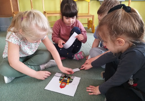 Czworo dzieci układa puzzle z wizerunkiem strażaka.