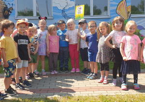 Dzieci stoją, trzymając tabliczkę "Szanuj zieleń".