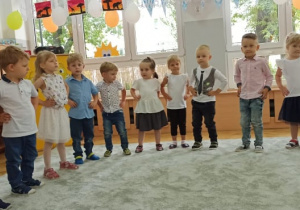 Dzieci ustawione w półkole śpiewają piosenkę.