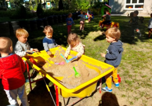 Kilkoro dzieci bawi się w piaskownicy konstrukcyjnej.