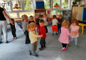 Dzieci tańczą na dywanie w małych kółeczkach.