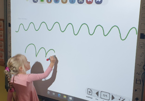 Dziewczynka pisze wzór na tablicy interaktywnej.
