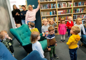 Dzieci oglądają pomieszczenie czytelni bibliotecznej.