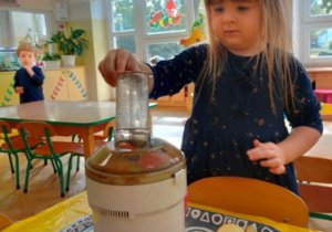 Dziewczynka przygotowuje dla siebie sok jabłkowo- gruszkowy.
