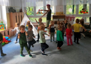 Dzieci maszerują w rytm muzyki po dywanie.