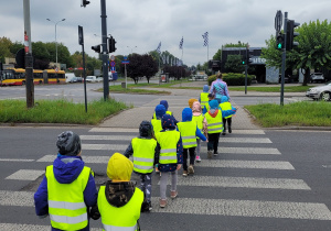 Dzieci przechodzą przez ulicę na zielonym świetle.