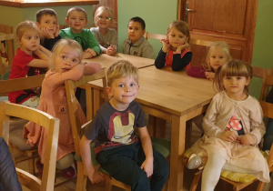 Grupa dzieci siedzie przy stole.