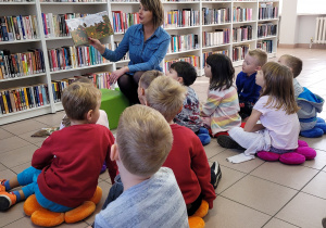 Dzieci słuchają czytanego przez panią bibliotekarkę opowiadania.