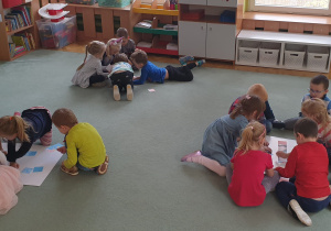 Dzieci na dywanie w trzech grupach ukaładają wspólnie obrazki.