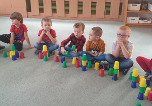Dzieci układają wieże z kolorowych kubeczków według wylosowanych kolorów.