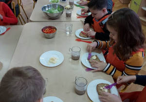 Dzieci samodzielnie smarują kanapki masłem.