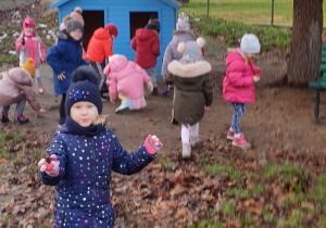 Dzieci szukają w ogrodzie przedszkolnym szyszek.