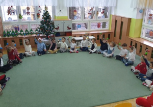 Dzieci siedzą na dywanie i grają na marakasach.