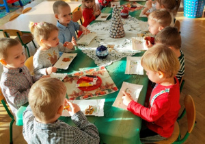 Dzieci z apetytem zjadają ozdobione przez siebie pierniczki.